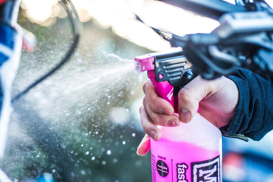 Person cleaning a bicycle with a pink muc off ultimate bike cleaning spray bottle, bike cleaning accessories