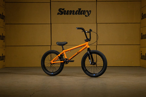 side view of the 18" Sunday bmx bike in orange, Sunday Primer kids BMX bike at a skatepark