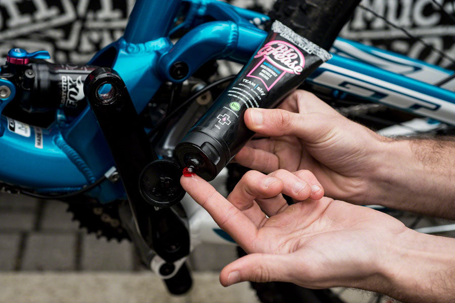 detailed view of Muc-off Bio grease being applied to a blue mountain bike, cycle bearing grease for mountain bikes 